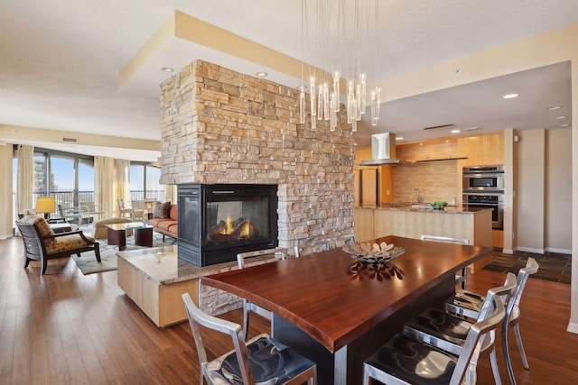 dining room featuring a textured ceiling, a fireplace, and dark hardwood / wood-style flooring