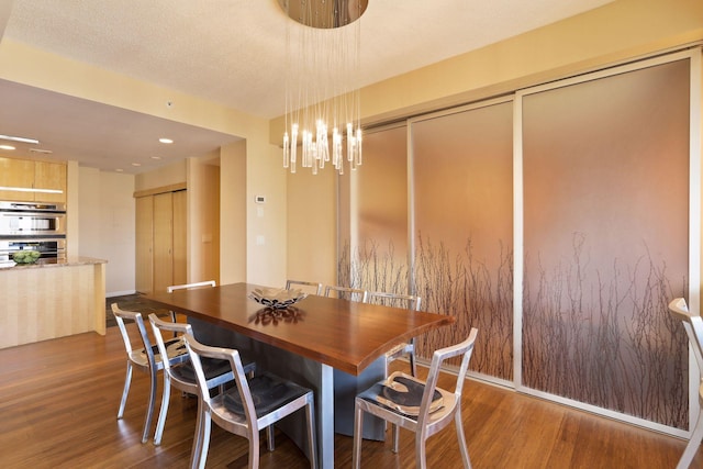 dining area featuring dark wood-type flooring, an inviting chandelier, and a textured ceiling