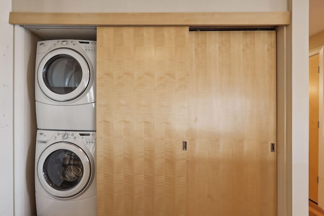 clothes washing area with stacked washing maching and dryer