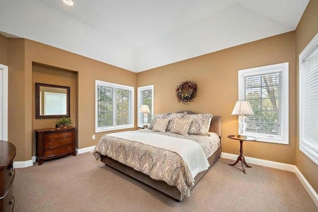 carpeted bedroom with vaulted ceiling and multiple windows