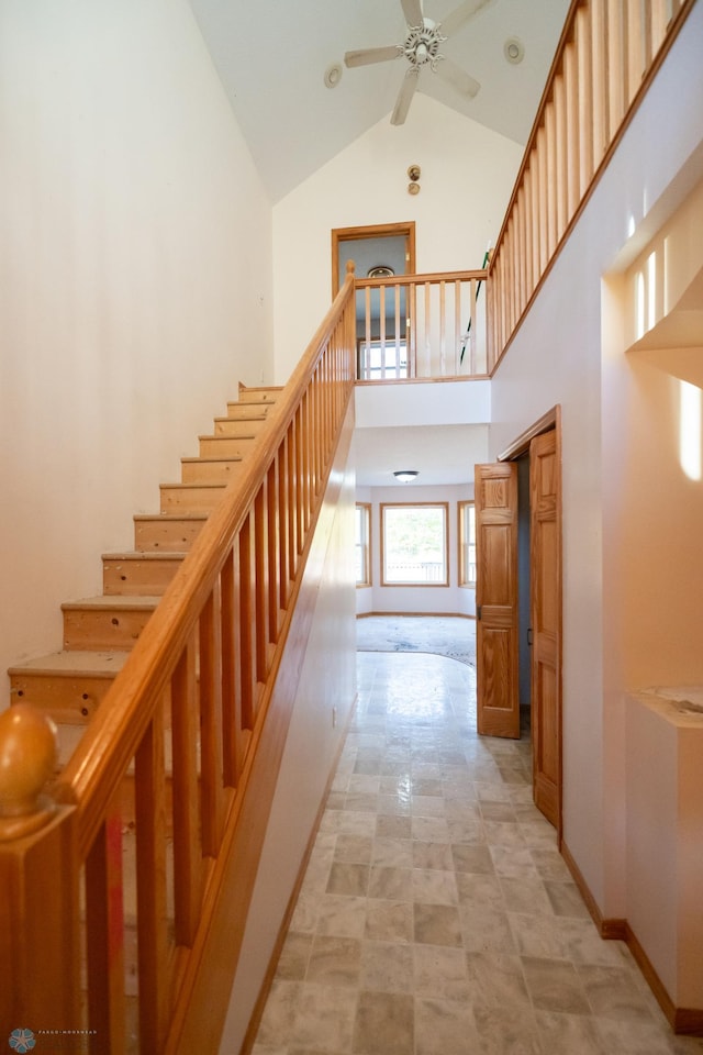 stairway with high vaulted ceiling and ceiling fan