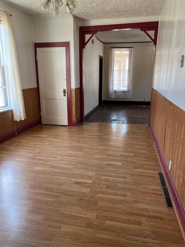 721 5th Ave E, Alexandria, MN 56308 - spare room with a wainscoted wall, wood finished floors, wood walls, and a textured ceiling