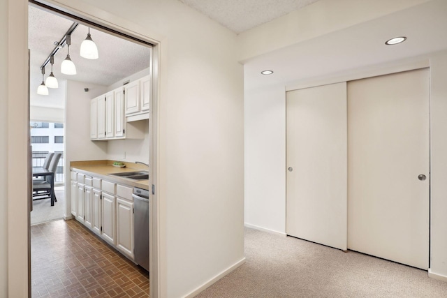 kitchen with dishwasher, hanging light fixtures, sink, and white cabinetry