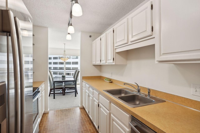 kitchen with stainless steel appliances, hanging light fixtures, sink, and white cabinetry