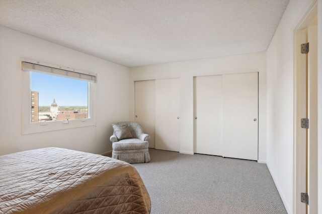 carpeted bedroom with multiple closets and a textured ceiling