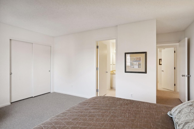 unfurnished bedroom with ensuite bathroom, carpet flooring, a closet, and a textured ceiling