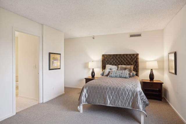 bedroom featuring light colored carpet, ensuite bath, and a textured ceiling