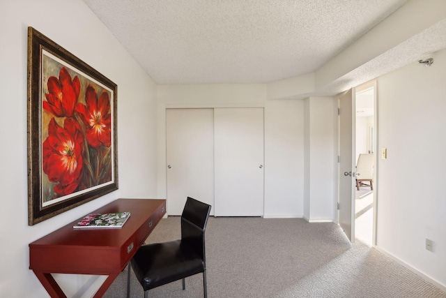 carpeted home office featuring a textured ceiling