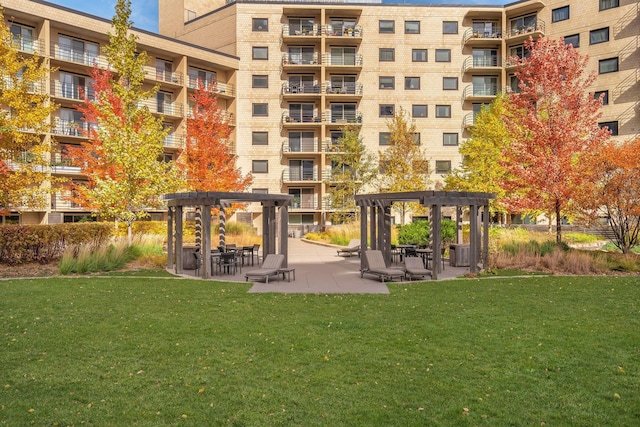 view of community featuring a patio, a lawn, and a pergola