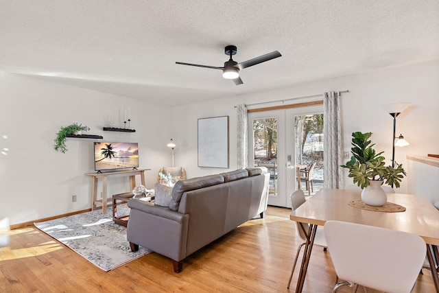 living room with french doors, ceiling fan, a textured ceiling, and light wood-type flooring