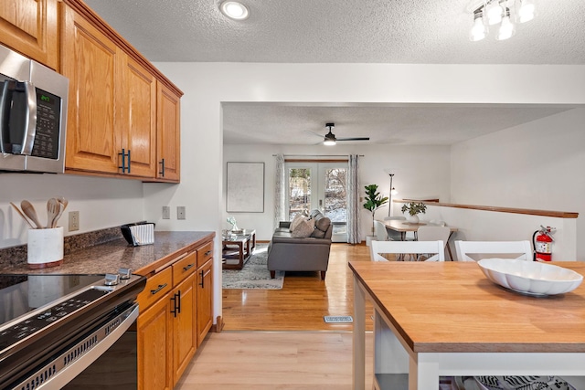 kitchen with ceiling fan, a textured ceiling, wood counters, and light hardwood / wood-style flooring