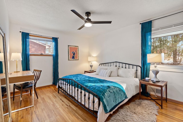 bedroom with a textured ceiling, light hardwood / wood-style floors, and ceiling fan