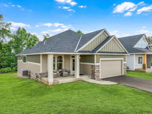 view of front of property featuring a front lawn, a porch, a garage, and cooling unit