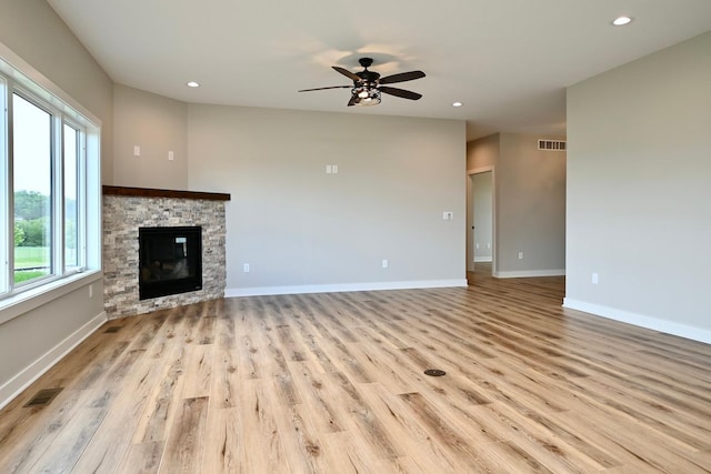 unfurnished living room with ceiling fan, a fireplace, and light wood-type flooring