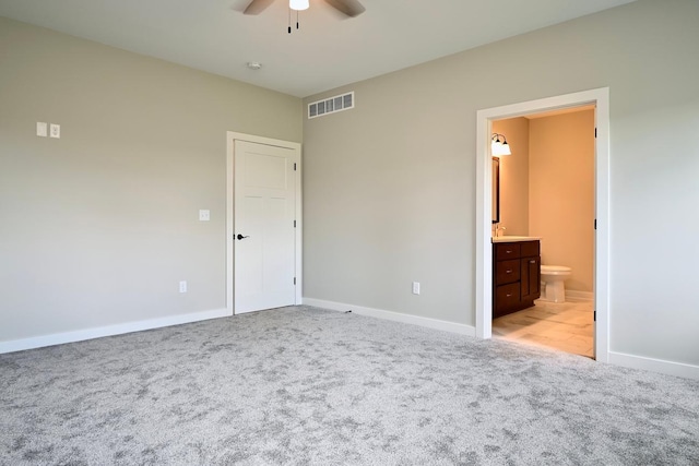 unfurnished bedroom featuring ceiling fan, ensuite bathroom, and light carpet