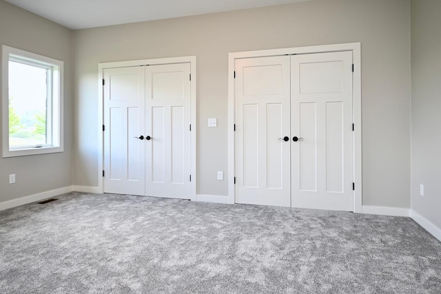 unfurnished bedroom featuring carpet flooring and multiple closets