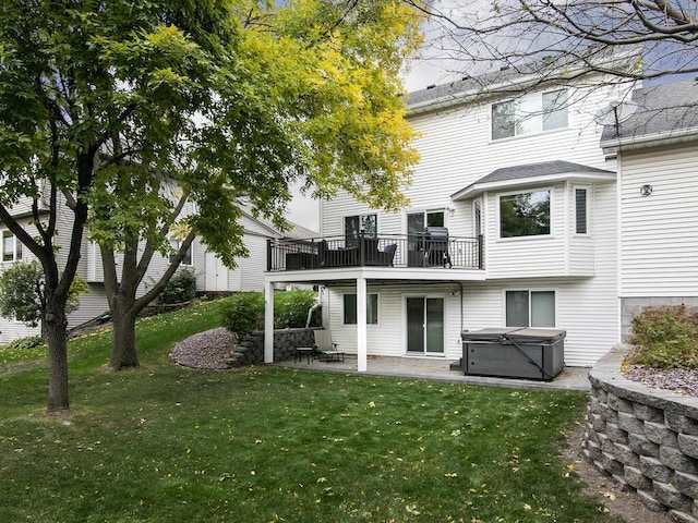 rear view of property with a patio area, a hot tub, and a lawn