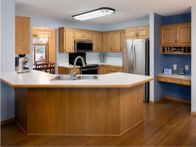 kitchen featuring appliances with stainless steel finishes, light countertops, a sink, and wood finished floors