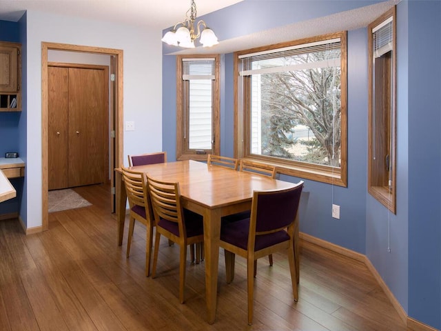 dining space with a notable chandelier, baseboards, and wood finished floors