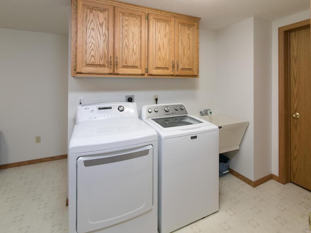 laundry room featuring washer and dryer, baseboards, cabinet space, and light floors