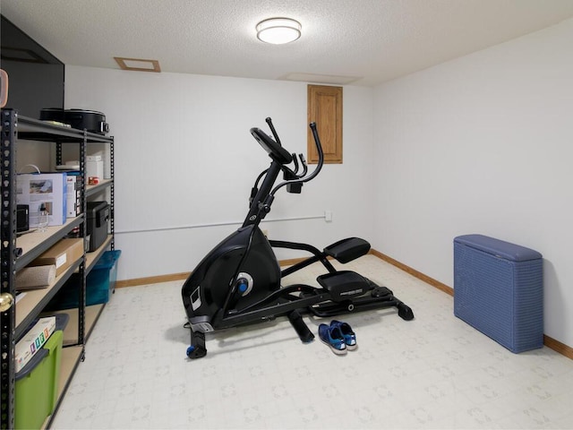 workout room with light floors, a textured ceiling, and baseboards