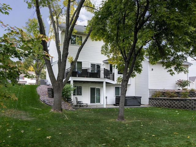 back of property with a yard, a patio, and a hot tub