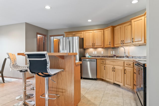 kitchen featuring a kitchen island, light tile patterned floors, a breakfast bar, sink, and stainless steel appliances