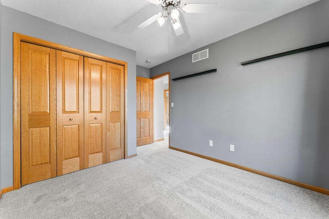 unfurnished bedroom featuring a closet, light colored carpet, and ceiling fan