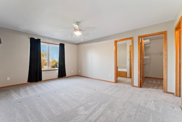 unfurnished bedroom with a closet, light carpet, a spacious closet, ensuite bathroom, and ceiling fan