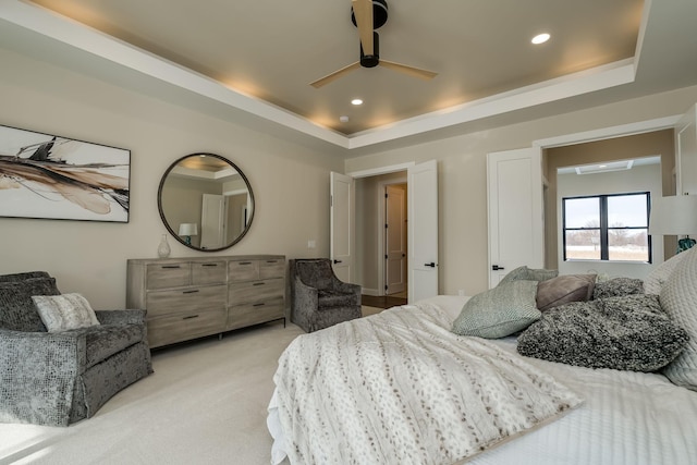 carpeted bedroom featuring ceiling fan and a tray ceiling