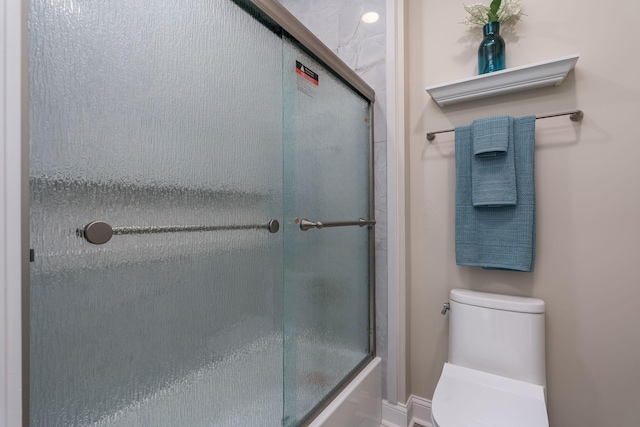 bathroom with toilet and combined bath / shower with glass door