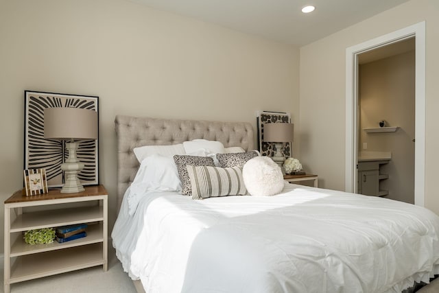 bedroom featuring ensuite bath and carpet flooring