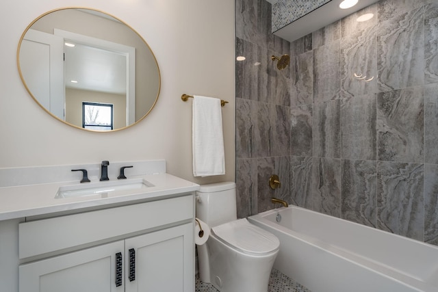 full bathroom featuring tiled shower / bath, vanity, and toilet