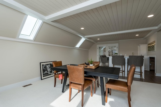 carpeted dining space with lofted ceiling with skylight