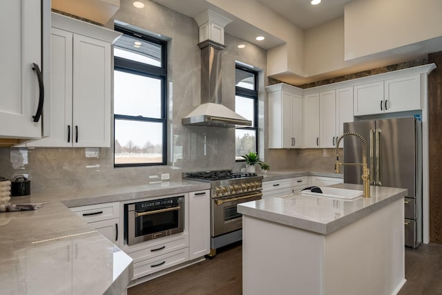 kitchen with white cabinetry, light stone countertops, an island with sink, and premium appliances