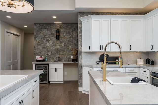 kitchen with dark wood-type flooring, wine cooler, sink, white cabinetry, and tasteful backsplash