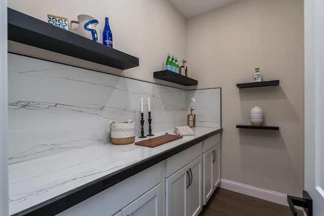 bar featuring light stone countertops, dark wood-type flooring, white cabinets, and decorative backsplash