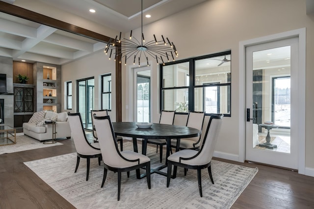 dining area with beamed ceiling, a large fireplace, a chandelier, hardwood / wood-style flooring, and coffered ceiling