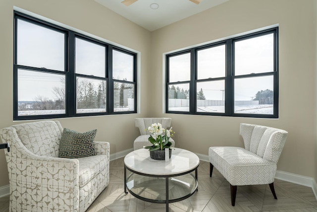 sitting room with ceiling fan and light parquet floors