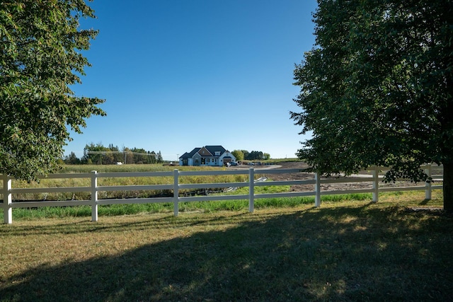 view of gate with a rural view and a lawn