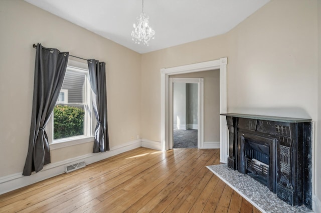 unfurnished living room with hardwood / wood-style floors and an inviting chandelier