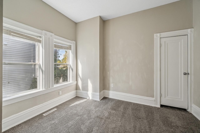 unfurnished room featuring dark colored carpet