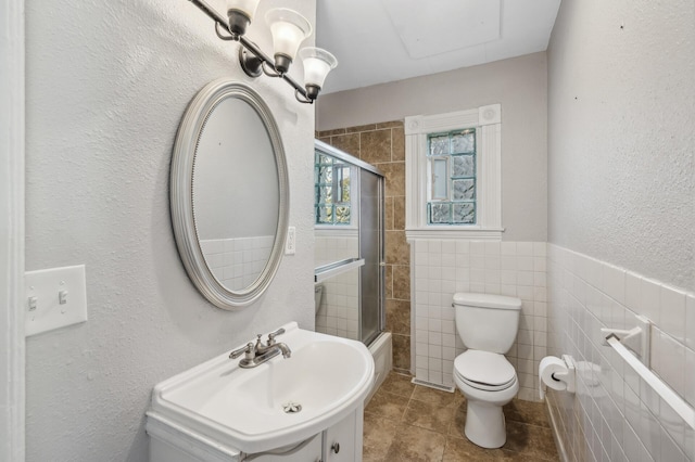 full bathroom featuring tile patterned flooring, combined bath / shower with glass door, toilet, tile walls, and vanity