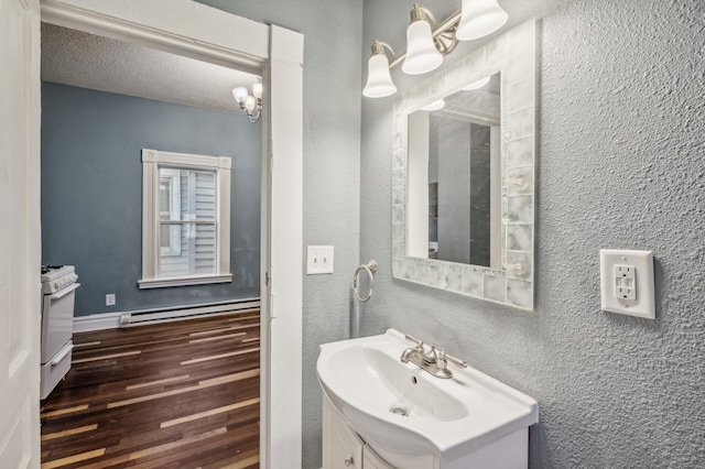 bathroom with a textured ceiling, hardwood / wood-style flooring, vanity, and a baseboard radiator