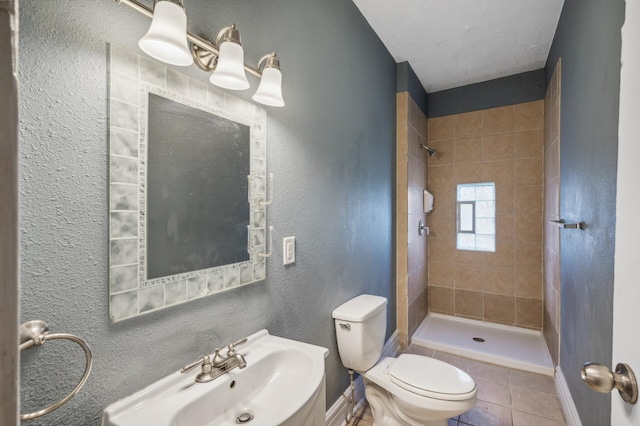 bathroom with sink, tile patterned flooring, toilet, and tiled shower