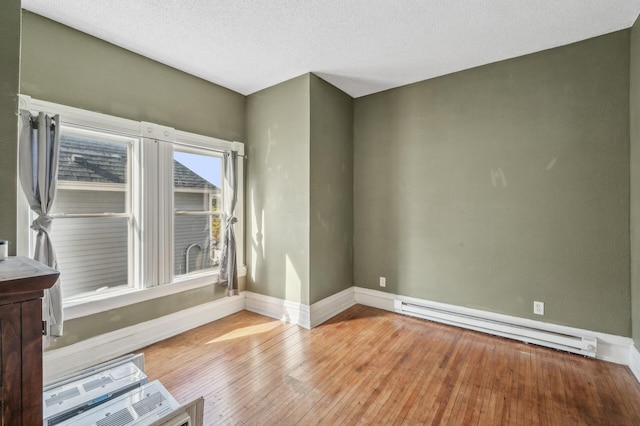 empty room featuring a baseboard radiator, light wood-type flooring, and a textured ceiling