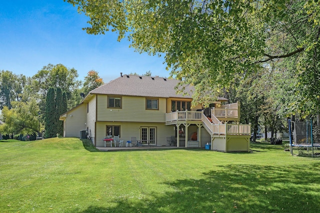 back of property with a yard, central air condition unit, a wooden deck, and a trampoline