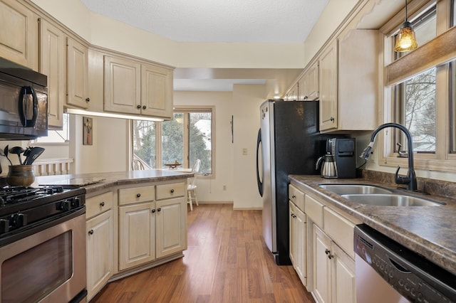 kitchen with wood finished floors, baseboards, a sink, appliances with stainless steel finishes, and a textured ceiling