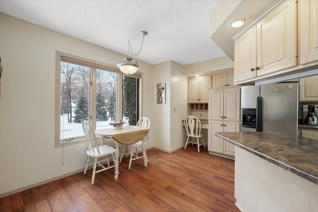 dining room with built in desk, a textured ceiling, baseboards, and wood finished floors