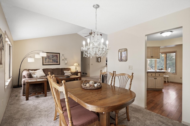 dining area with vaulted ceiling, a notable chandelier, light wood finished floors, and light carpet